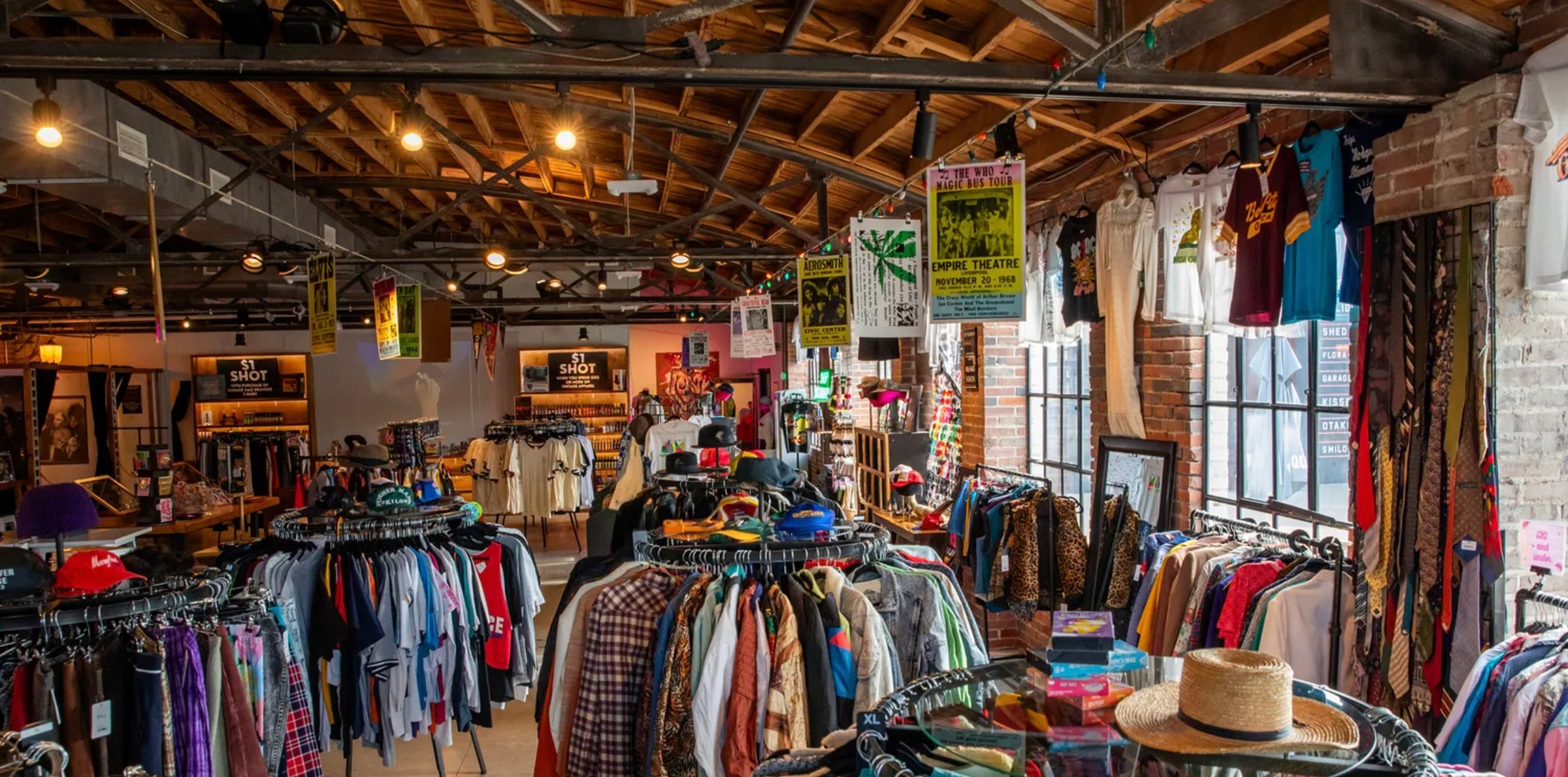 Vintage clothing store with racks of clothes art, hats ties, and posters on the walls.